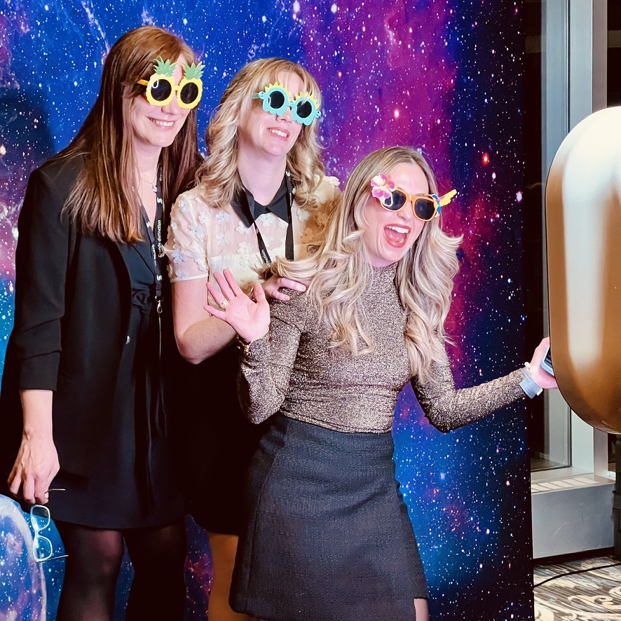 Trois invitées utilisent un photobooth lors d’un événement corporatif
